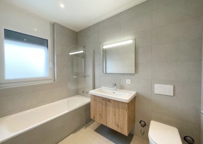 Salle de bains équipée d'une baignoire, grande vasque avec meuble sous-vasque, mirroir et WC